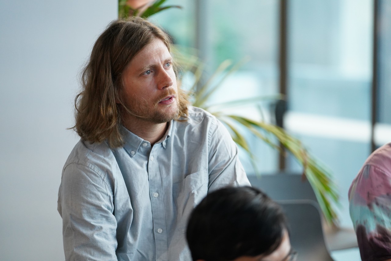 Jakub Szewczuk author for Spektrumlab.io A thoughtful man listening attentively during a discussion in a modern indoor setting.